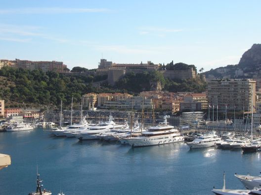 El puerto principal está lleno de yates monumentales. Detrás, los restos de la carrera y al fondo el palacio.